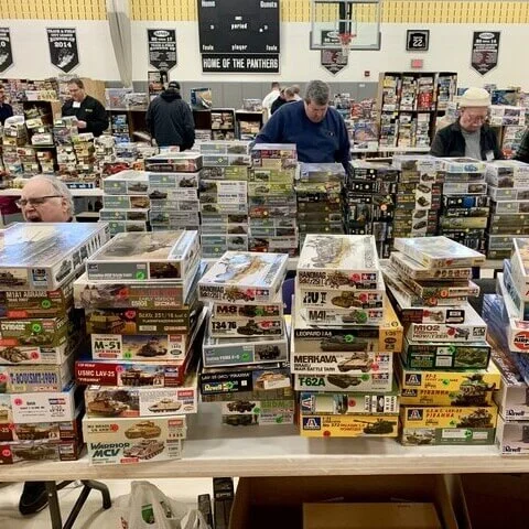 A fluffy orange and white cat inspects a collection of model kits.